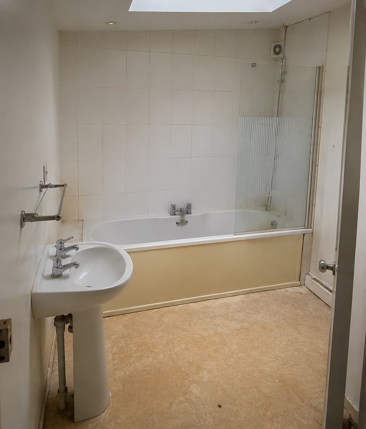 The bathroom before: dated cream tiles, old pedestal basin and a worn bath.